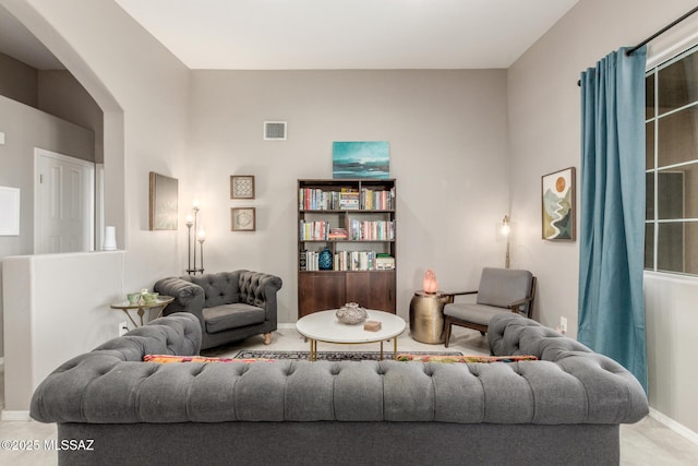 living area featuring arched walkways, visible vents, and baseboards