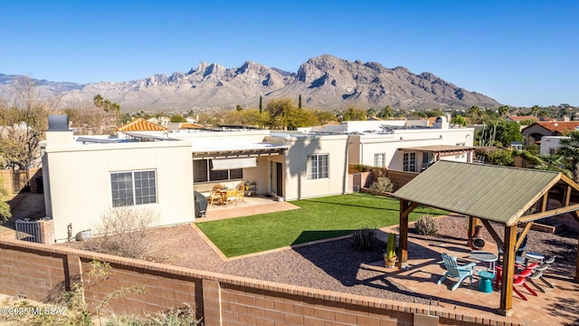 back of property with a yard, a patio, stucco siding, fence, and a mountain view