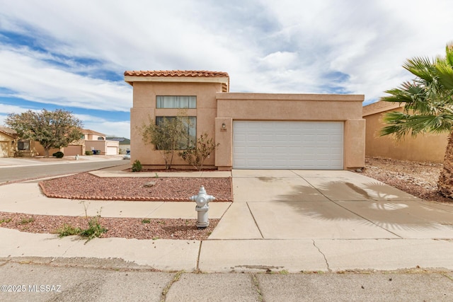 mediterranean / spanish home with driveway, an attached garage, a tiled roof, and stucco siding