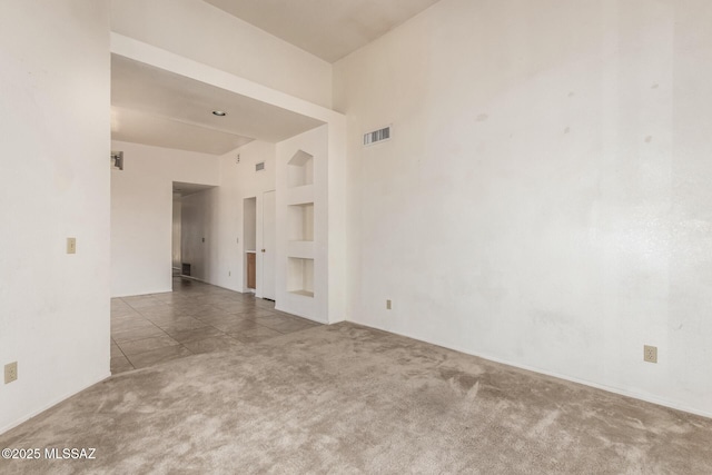 spare room featuring carpet floors, tile patterned flooring, and visible vents