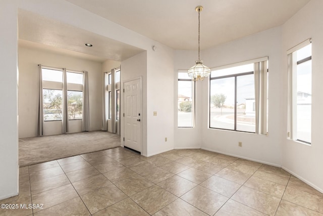 tiled spare room featuring carpet floors, baseboards, and an inviting chandelier