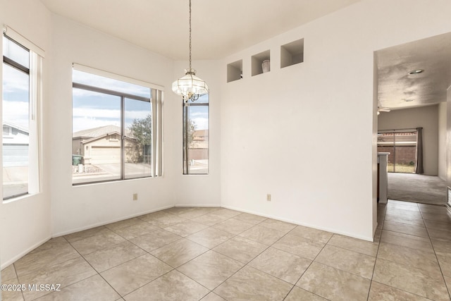 tiled spare room with baseboards and a notable chandelier