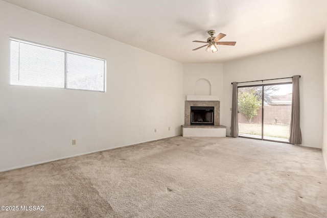 unfurnished living room featuring carpet, a ceiling fan, and a tile fireplace