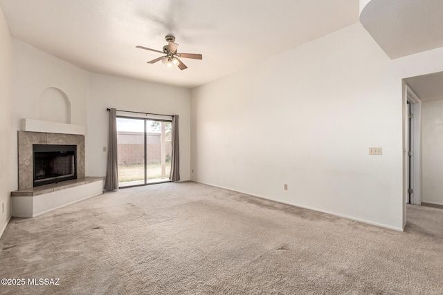 unfurnished living room with carpet floors, ceiling fan, baseboards, and a tile fireplace