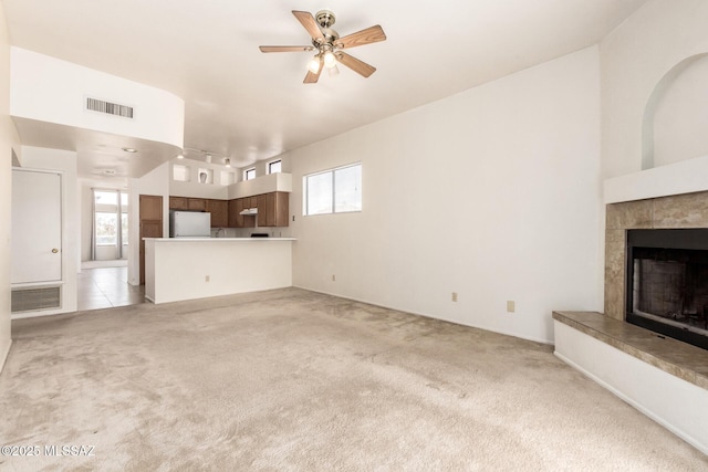 unfurnished living room with light carpet, plenty of natural light, a tile fireplace, and visible vents