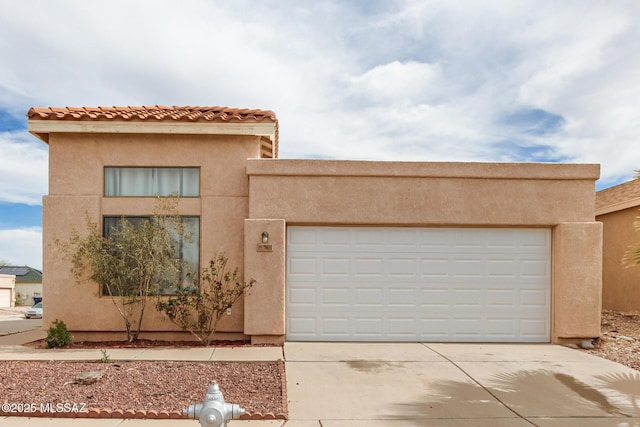 view of front of property with driveway, an attached garage, and stucco siding