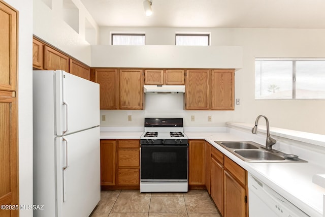 kitchen with white appliances, light countertops, under cabinet range hood, a sink, and light tile patterned flooring