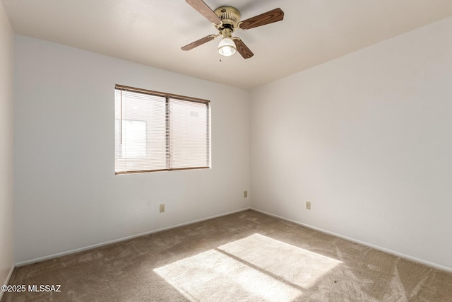 carpeted empty room featuring a ceiling fan and baseboards