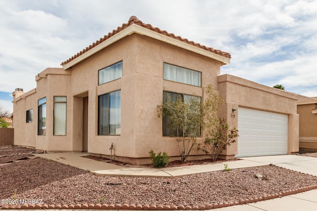 view of front of property featuring a garage, concrete driveway, and stucco siding