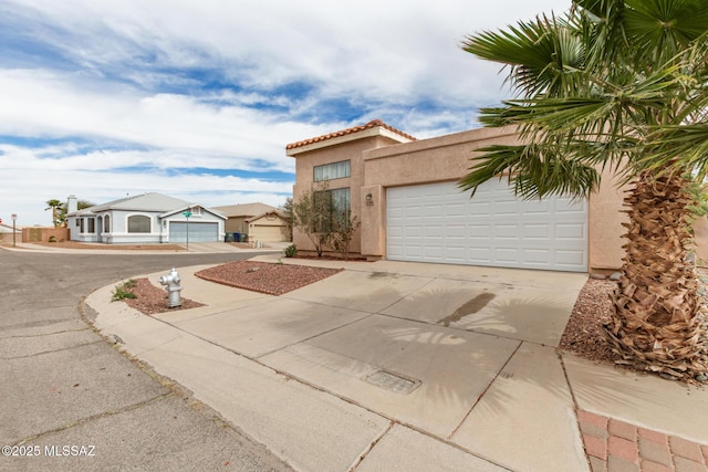 mediterranean / spanish house featuring concrete driveway, a tile roof, an attached garage, and stucco siding