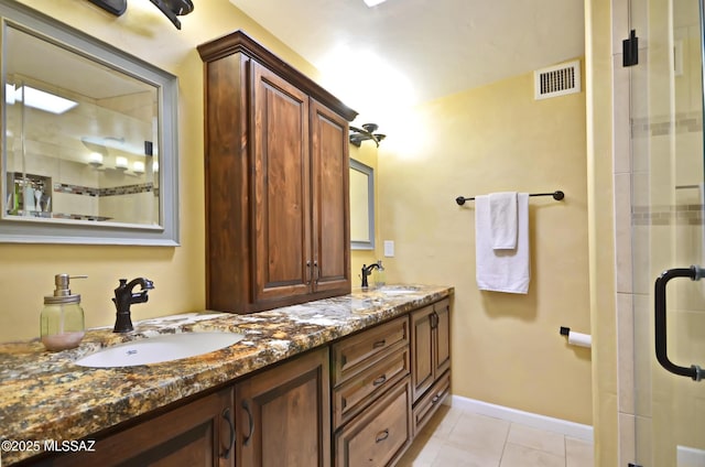 bathroom featuring a shower with door, tile patterned flooring, visible vents, and a sink