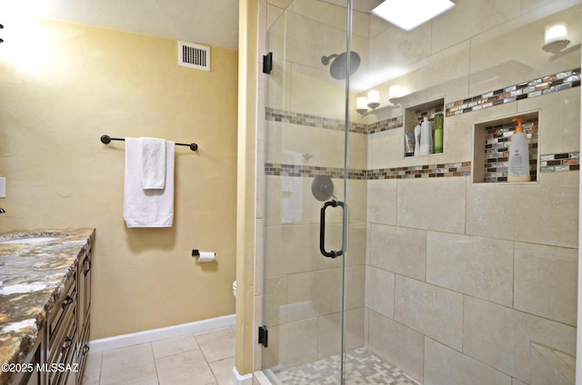 bathroom with visible vents, vanity, a shower stall, baseboards, and tile patterned floors