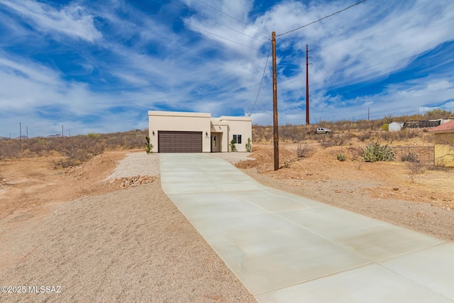 pueblo revival-style home with driveway, an attached garage, and stucco siding