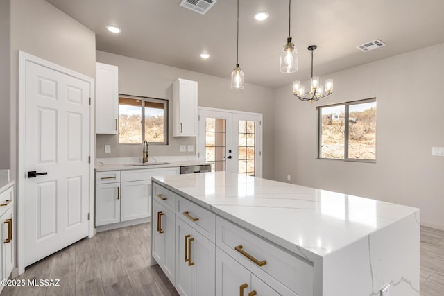 kitchen featuring visible vents, dishwasher, french doors, light wood-style floors, and a sink