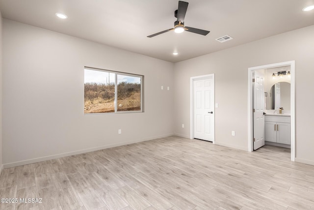 unfurnished bedroom featuring arched walkways, recessed lighting, and light wood-style floors