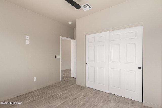 unfurnished bedroom with light wood-type flooring, baseboards, visible vents, and a closet