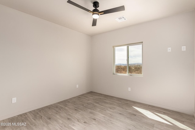 spare room featuring light wood finished floors, baseboards, visible vents, and a ceiling fan