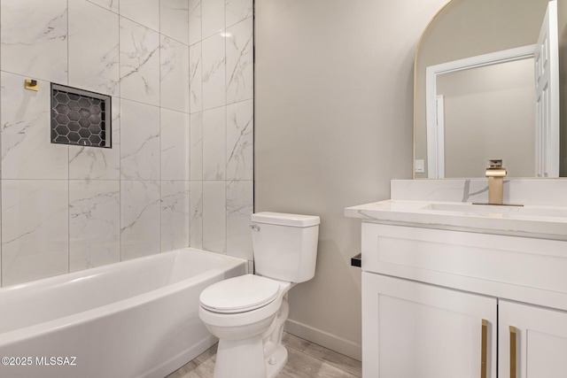 bathroom with toilet, wood finished floors, vanity, baseboards, and shower / washtub combination