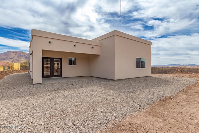 back of house with a patio, french doors, a mountain view, and stucco siding