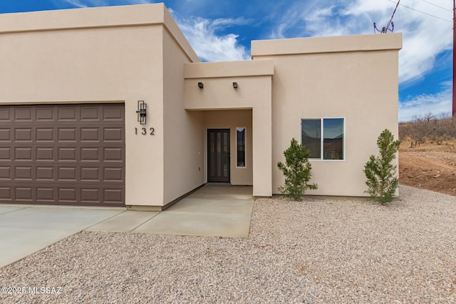 view of front of house featuring a garage, concrete driveway, and stucco siding