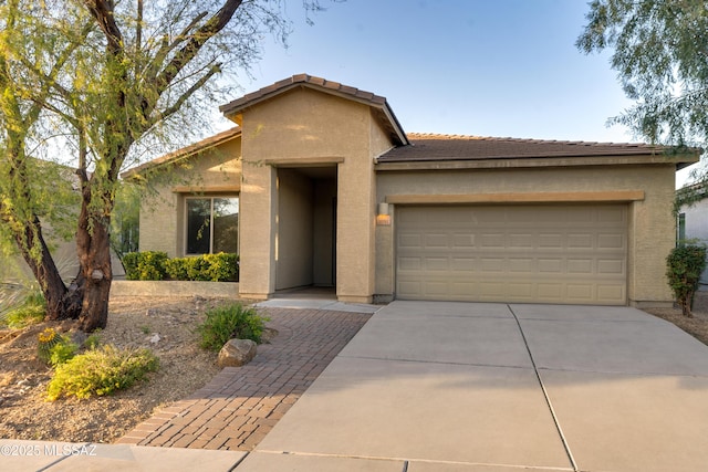 view of front of house featuring concrete driveway, an attached garage, a tiled roof, and stucco siding