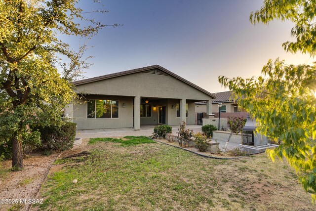 1091 E Empire Canyon Ln, Sahuarita, AZ 85629 - rear view of house with stucco siding, a patio, and a lawn