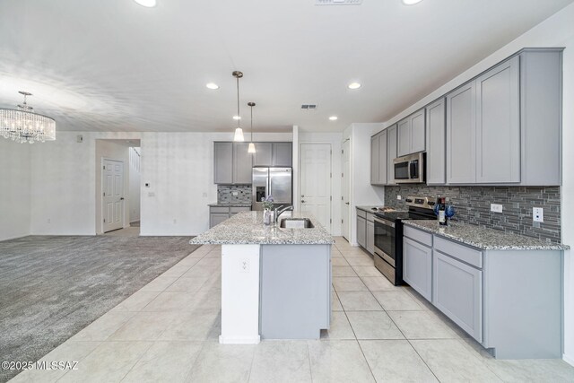 kitchen featuring stainless steel appliances, a sink, light colored carpet, and gray cabinetry