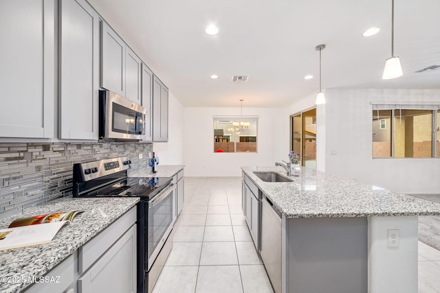 kitchen with a sink, visible vents, appliances with stainless steel finishes, gray cabinets, and an island with sink