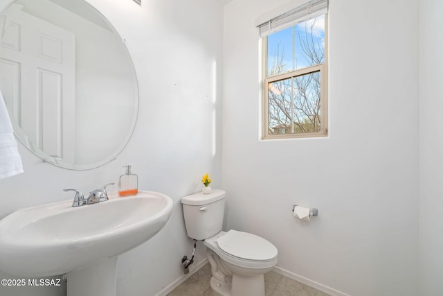 half bathroom featuring toilet, baseboards, a sink, and tile patterned floors