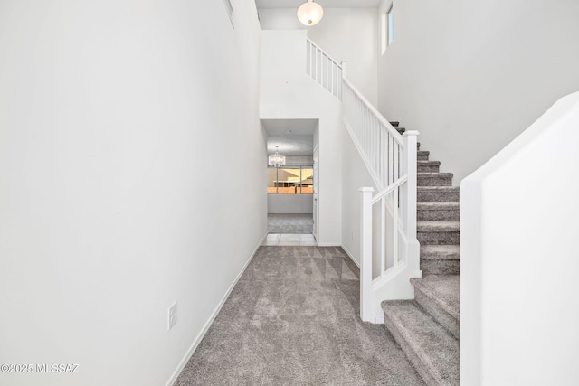 stairs with a towering ceiling, baseboards, and carpet flooring