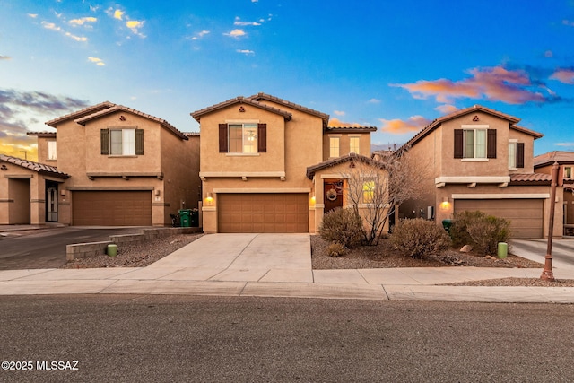 mediterranean / spanish-style house with an attached garage, driveway, a tile roof, and stucco siding