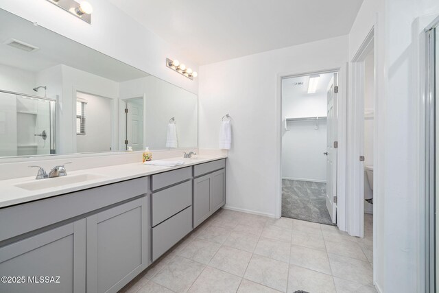 bathroom with tile patterned flooring, toilet, a sink, a shower stall, and double vanity