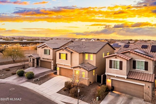 view of front of home featuring a garage, solar panels, concrete driveway, a tiled roof, and stucco siding