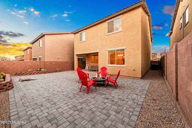 back of house with a fenced backyard, a patio, a fire pit, and stucco siding