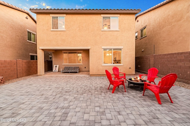 rear view of property with a patio area, an outdoor fire pit, fence, and stucco siding