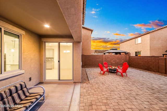 patio terrace at dusk featuring a fire pit and fence