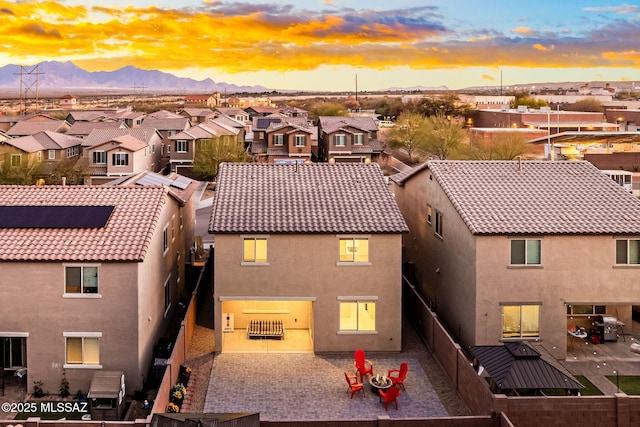 exterior space featuring a patio, a tile roof, a residential view, a mountain view, and stucco siding