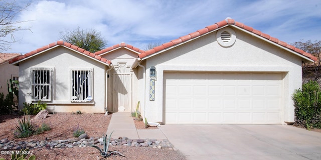 mediterranean / spanish-style house with driveway, an attached garage, a tiled roof, and stucco siding