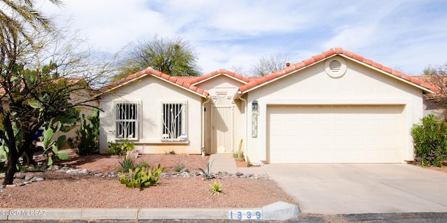 view of front facade with a garage, concrete driveway, a tiled roof, and stucco siding