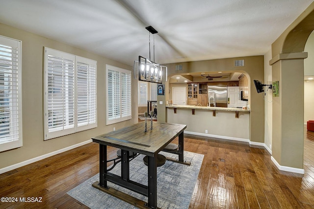 dining area featuring baseboards, arched walkways, and hardwood / wood-style floors