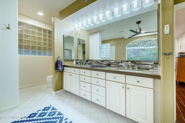 bathroom with a sink, tasteful backsplash, ceiling fan, and double vanity