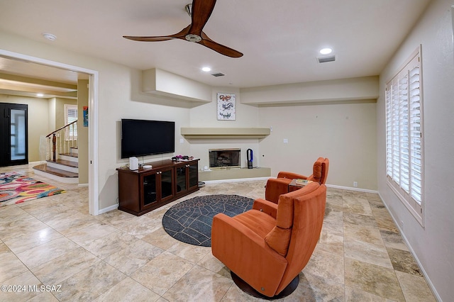 living room featuring visible vents, stairs, baseboards, and a glass covered fireplace