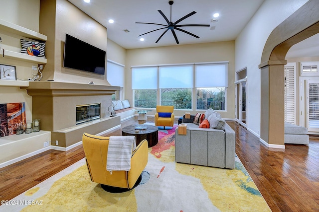 living area with baseboards, recessed lighting, a fireplace, wood finished floors, and arched walkways