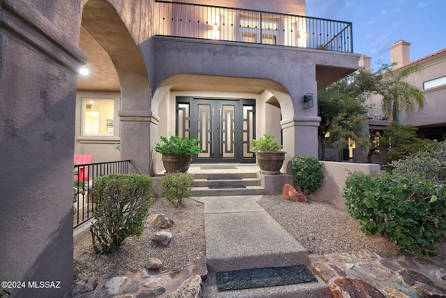 entrance to property with a balcony and stucco siding