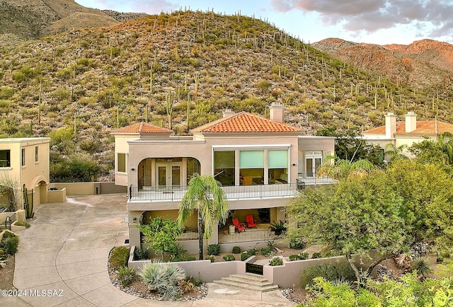 exterior space featuring a balcony, french doors, a mountain view, and stucco siding