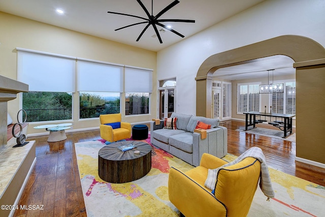 living area featuring arched walkways, baseboards, and wood-type flooring