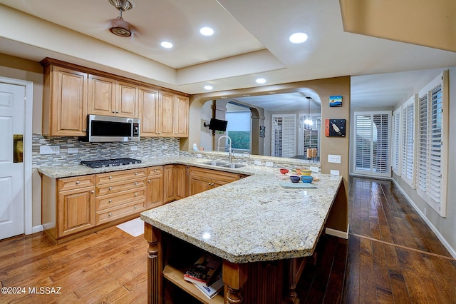 kitchen featuring open shelves, arched walkways, stainless steel appliances, a sink, and hardwood / wood-style flooring