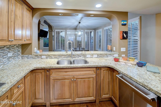 kitchen featuring a sink, light stone counters, stainless steel dishwasher, and a peninsula