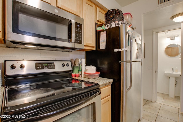 kitchen featuring light tile patterned floors, stainless steel appliances, light brown cabinetry, and visible vents