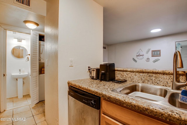 kitchen featuring light tile patterned floors, visible vents, stainless steel dishwasher, a sink, and stacked washing maching and dryer